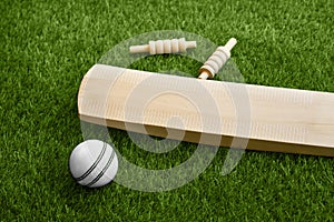 Cricket bat ball stumps and bails placed on green grass cricket pitch background