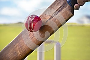 Cricket player batsman hitting ball with stumps on cricket pitch