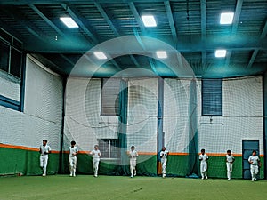 Cricket practice indoor club cricket lights on astrotruff men in white cricketers jogging inside the indoor stayindoors