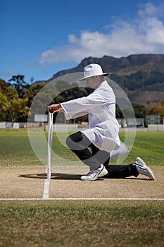 Cricket umpire putting bails on stumps at field