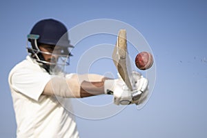 A cricketer playing cricket on the pitch in white dress for test matches. Sportsperson hitting a shot on the cricket ball photo