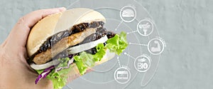 Crickets insect for eating as food items made of cooked insect in burger and vegetable on woman`s hand with media icons nutrition