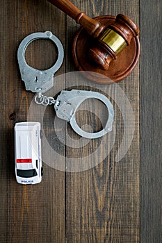 Crime concept. Police car toy, handcuff, judge hammer on dark wooden background top view space for text