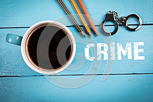 CRIME, law, investigation and court concept. Coffee mug and miniature handcuffs on a wooden table