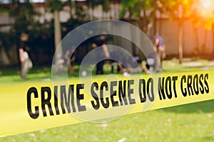 Crime scene tape and blurred law enforcement team background