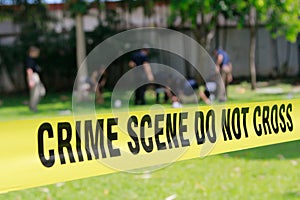 Crime scene tape and blurred law enforcement team background