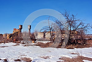 Crimean coquina rock blocks ruined farm walls, two water towers, dry weathered grass field covered with snow, elderberry bushes