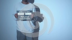 A criminal is being photographed. Mugshot sign