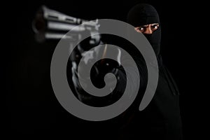 Criminal with black mask holding pistol, standing shooting with a gu