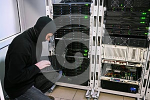 Criminal in black mask steals information from the database of modern datacents. Virus attack in server room. A hacker with a