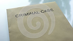 Criminal case, folder with important police documents lying on table, close up