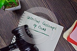 Criminal Contempt of Court write on a book isolated on Wooden Table