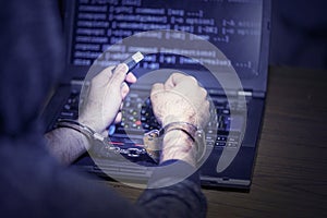 Criminal hacker hands locked in handcuffs. Close-up view