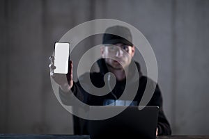 Criminal hacker using laptop computer while working in dark office