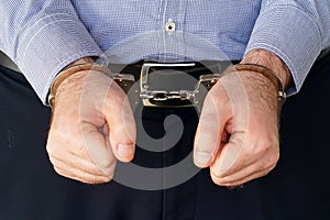 Criminal hands locked in handcuffs. Close-up view