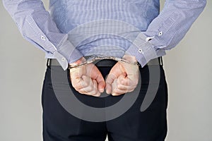 Criminal hands locked in handcuffs. Close-up view