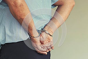 Criminal hands locked in handcuffs. Close-up view