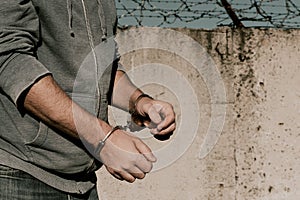 Criminal in jail. A handcuffed man stands against a barbed wire wall. Prisons. Law and order. Handcuffs