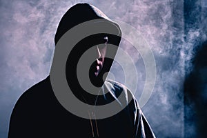 Criminal man in shadow. Scary suspicious stranger with hidden face. Silhouette of gangster with dark smoke fog background.