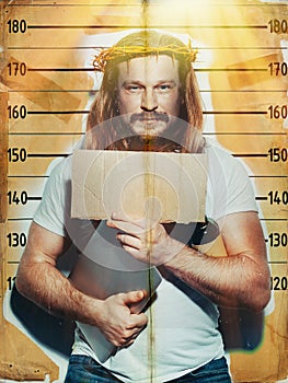 Criminal suspect Jesus holds a laptop and a bottle of alcohol in his hand, is photographed against the background of growth wall