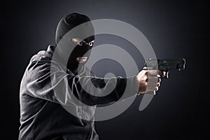 Criminal wearing black balaclava and hoodie with a gun