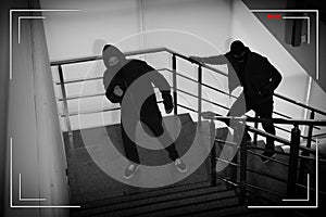 Criminals in masks on stairs, view through CCTV camera