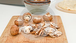 Crimini mushroom slices close up on wooden cutting board, preparation process