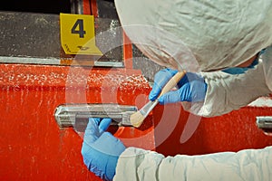 Criminologist technician collecting evidences from burned car on location of crime