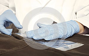 Criminologist technician at work on evidence of microtraces with acetate foil