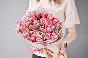 Crimson color tulips in woman hand. Spring bouquet of red tulips in hands. Bunch of fresh cut spring flowers