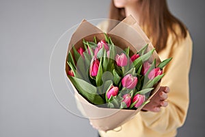 Crimson color tulips in woman hand. Spring bouquet of red tulips in hands. Bunch of fresh cut spring flowers