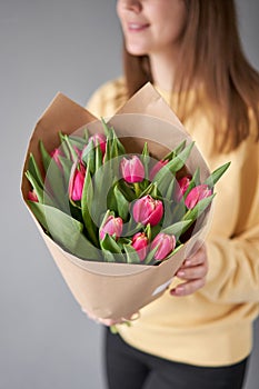 Crimson color tulips in woman hand. Spring bouquet of red tulips in hands. Bunch of fresh cut spring flowers