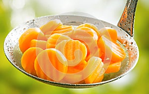 Crinkle cut sliced carrots in a kitchen ladle