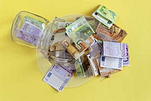 Crisis and budget deficit concept. Money and empty glass money jar. Euro banknotes, money box. Income, savings photo