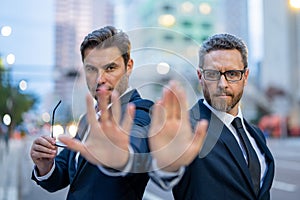 Crisis, risk. Two handsome business men in suit doing stop sing with hand. Warning expression with negative and serious