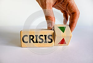 Crisis symbol. Wooden cube with word `crisis`. Businessman turns the wooden cube, changes the direction of an arrow down or up.