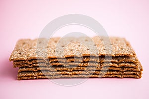 Crisp bread on the pink background. Corn dodger. Crackers. Loaf of bread