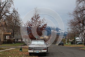 A crisp fall day looking down the street of a small town in Oregon, with snow creeping down the mountain