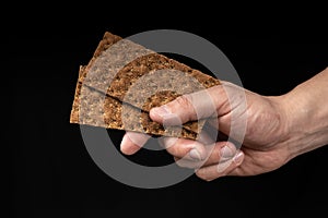 Crisp whole grain breads in the male hand on black background