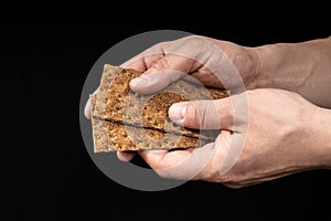 Crisp whole grain breads in the male hand on black background