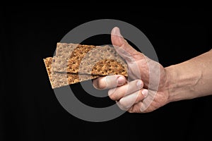 Crisp whole grain breads in the male hand on black background