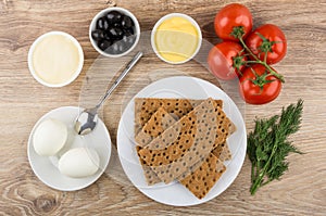 Crispbread in plate and ingredients for sandwiches on wooden tab