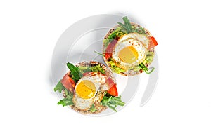 Crispbread sandwich with guacamole, arugula, tomatoes and quail egg isolated on a white background. Bruschetta with