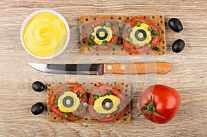 Crispbread with tomatoes, mayonnaise, scallion and olives, knife