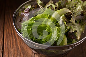 Crisphead lettuce in a bowl on wooden table.
