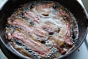 Crispy bacon frying in an iron pan