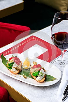 Crispy bruschetta with salmon, cheese, seaweed. Glass of red wine. Place for text