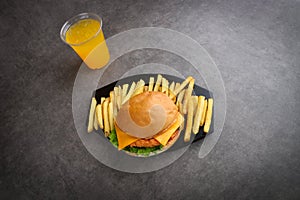 Crispy chicken burger and fries and orange juice on a gray background - kids meal