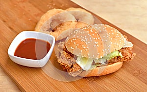 Crispy chicken burger with vegetables on wood background