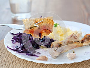 Crispy chicken skin on fork over scraps of leftover food and chicken bones photo